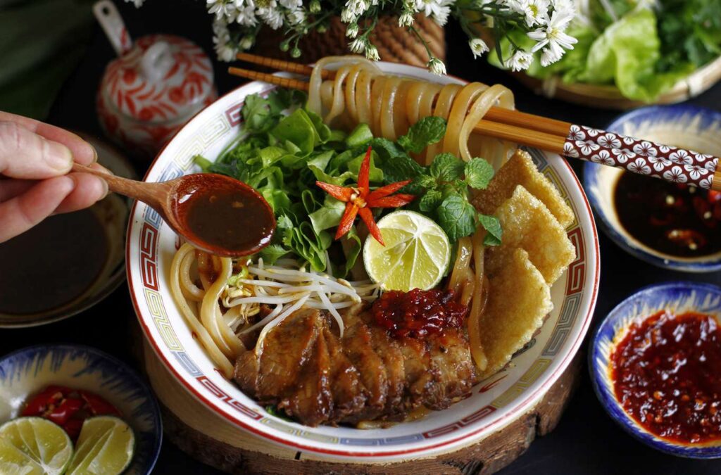 Cao Lau combines chewy noodles, char siu pork, and Tra Que’s fresh vegetables.
